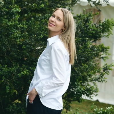Maria, den ene af kvinderne bag Ro På, i hvid skjorte foran grønne buske